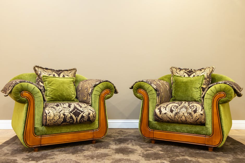 An ornate armchair with a wooden frame featuring carved details, upholstered in a patterned fabric with shades of blue, green, and beige. The upholstery is heavily damaged, torn, and missing in several areas, revealing the internal padding and the frame beneath. The chair is situated outdoors on a paved surface, with a concrete background. The setting appears to be a street or driveway, and the lighting is natural. This image relates to domestic cleaning services offered by Carpet Cleaners W9, highlighting the importance of upholstery deep cleaning and maintenance.